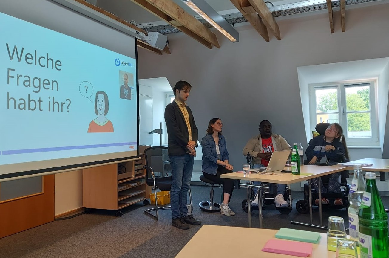 4 Personen halten einen Vortrag. Auf der Leinwand steht: Welche Fragen habt ihr?