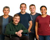 Fotorealistisches KI-Bild: Eine Gruppe aus fünf Personen steht zusammen und lächelt. Es sind 3 Männer und 2 Frauen, eine Person hat einen Rollstuhl.
